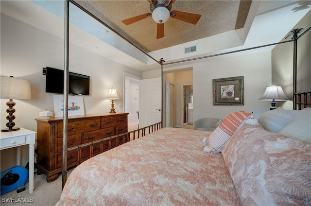 carpeted bedroom with ceiling fan and a raised ceiling