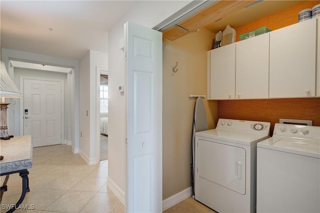 laundry area with washing machine and clothes dryer, light tile patterned floors, and cabinets