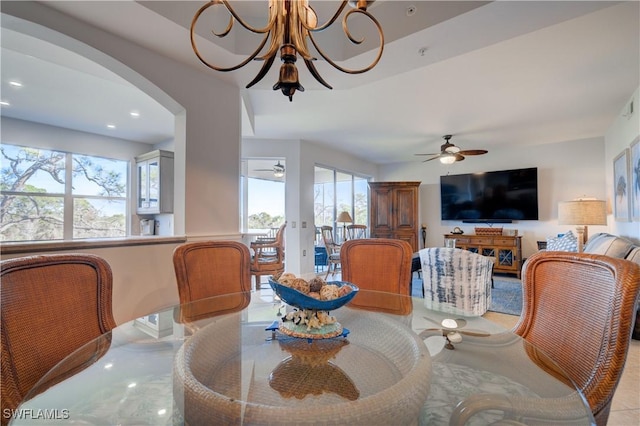 dining space with ceiling fan with notable chandelier and light tile patterned flooring