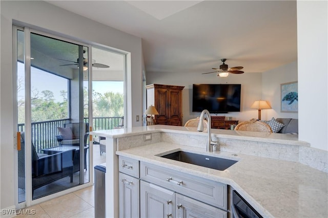 kitchen with ceiling fan, light stone counters, light tile patterned floors, and sink