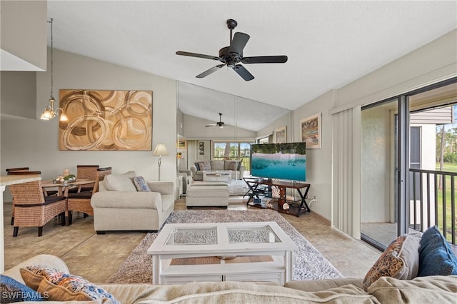 living room featuring vaulted ceiling, a wealth of natural light, and ceiling fan with notable chandelier