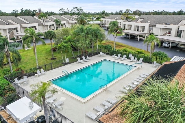 community pool featuring a patio area, fence, and a residential view