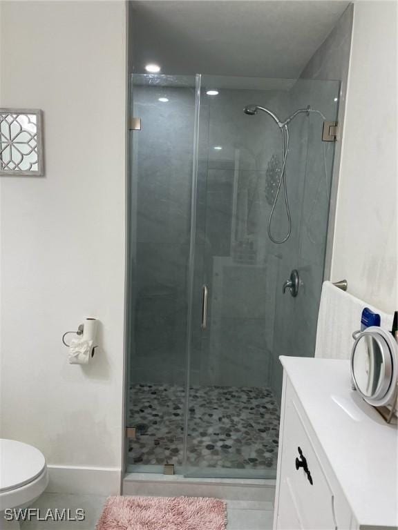 bathroom with tile patterned floors, toilet, vanity, and walk in shower