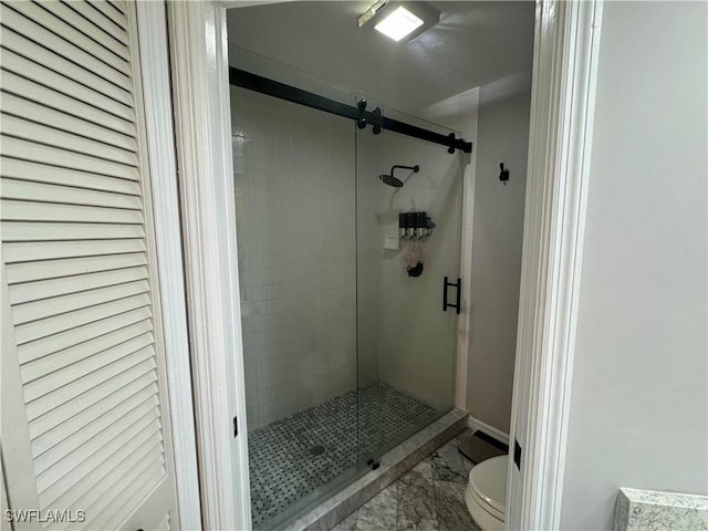 bathroom featuring toilet and a shower with door