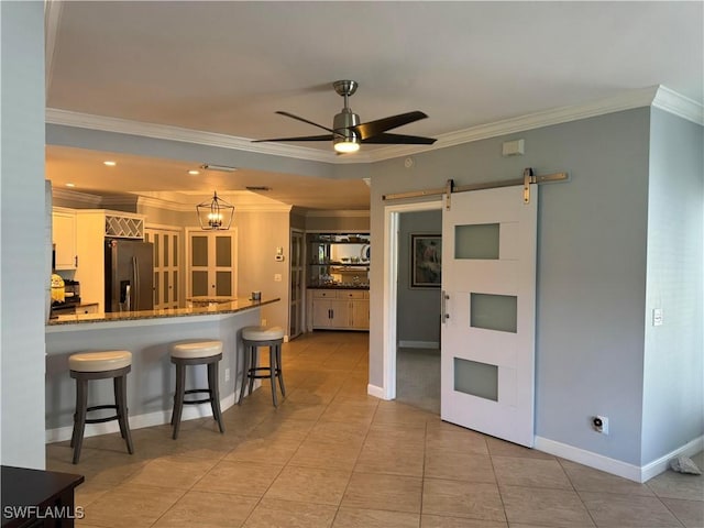 kitchen with white cabinetry, stone counters, a barn door, stainless steel fridge with ice dispenser, and ornamental molding