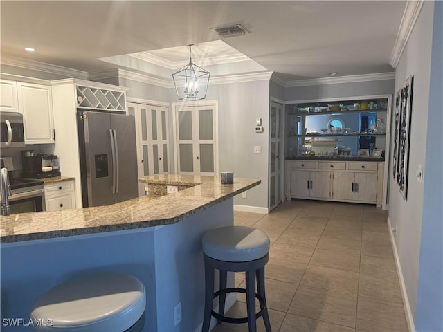 kitchen featuring a kitchen bar, pendant lighting, stainless steel appliances, and ornamental molding