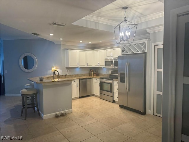 kitchen featuring kitchen peninsula, appliances with stainless steel finishes, stone counters, white cabinetry, and hanging light fixtures