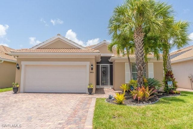 mediterranean / spanish home featuring a garage and a front lawn