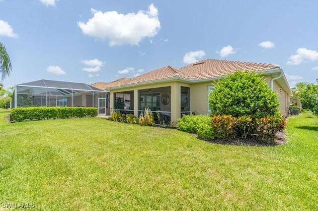 rear view of house featuring a lanai and a yard