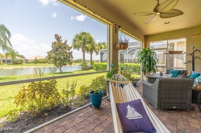 sunroom with ceiling fan and a water view