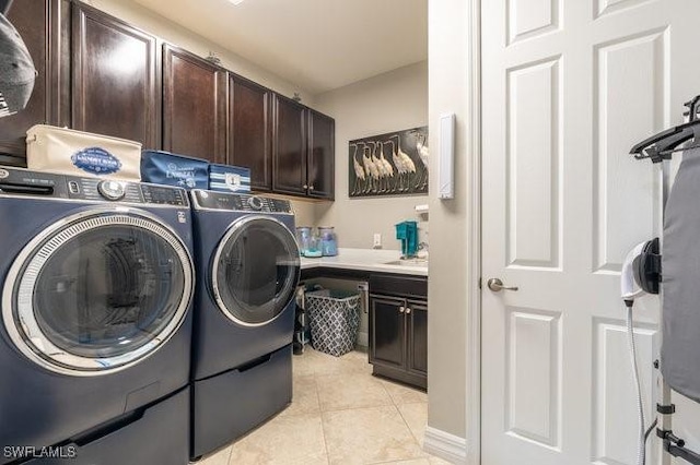 clothes washing area featuring cabinets, light tile patterned floors, and washer and dryer