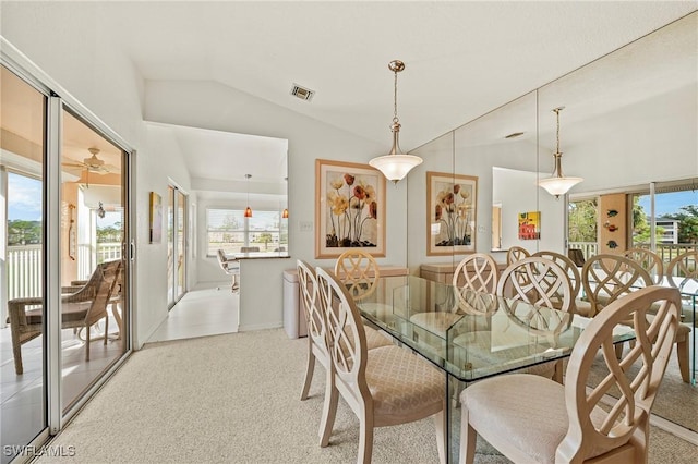 carpeted dining space featuring lofted ceiling and a healthy amount of sunlight