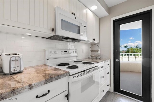 kitchen with white appliances, light stone countertops, decorative backsplash, and white cabinets