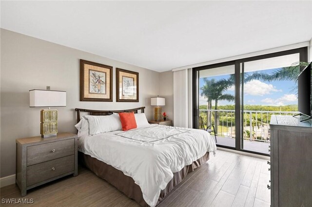 bedroom with expansive windows, access to exterior, and hardwood / wood-style floors