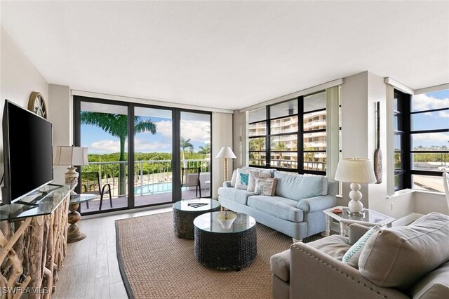 living room with a healthy amount of sunlight, floor to ceiling windows, and hardwood / wood-style floors