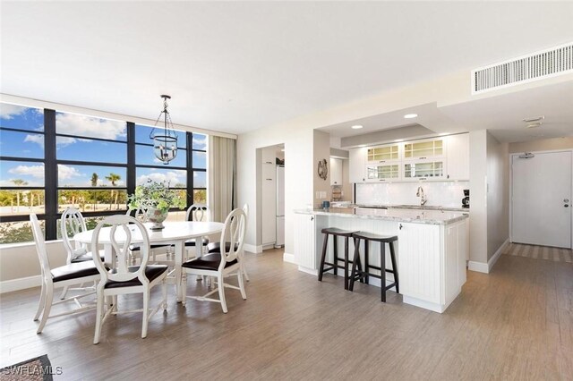 dining space with floor to ceiling windows, sink, a chandelier, and hardwood / wood-style floors