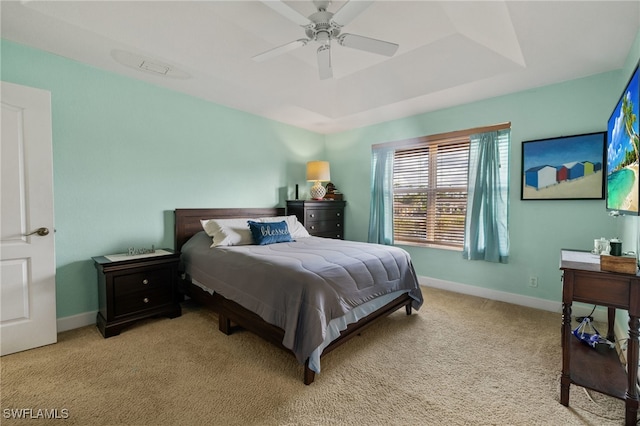 bedroom with a tray ceiling, ceiling fan, and light carpet