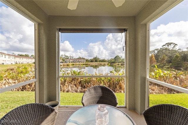 sunroom / solarium with a water view, plenty of natural light, and ceiling fan