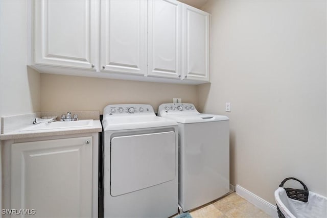 clothes washing area with washer and dryer, sink, and cabinets