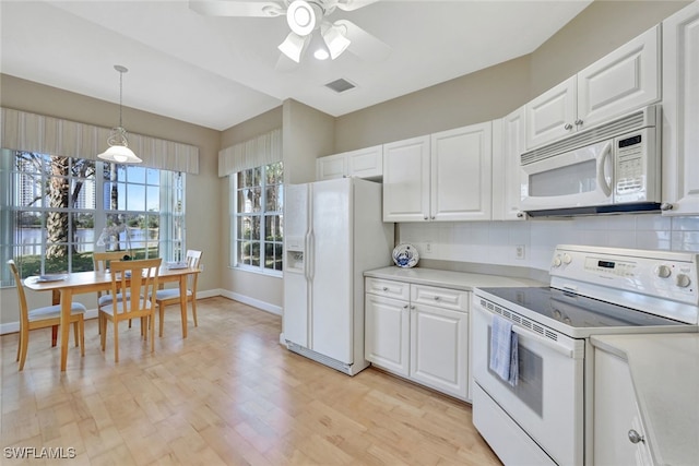 kitchen with white appliances, white cabinets, light hardwood / wood-style flooring, and hanging light fixtures