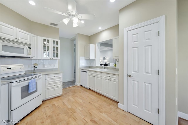 kitchen featuring tasteful backsplash, visible vents, light wood-style flooring, white appliances, and a sink