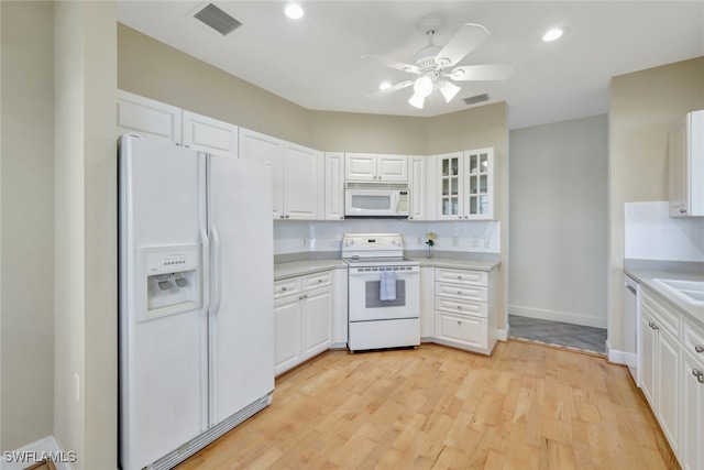 kitchen with white appliances, white cabinets, and visible vents