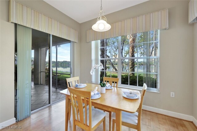 dining area featuring light hardwood / wood-style flooring and a water view