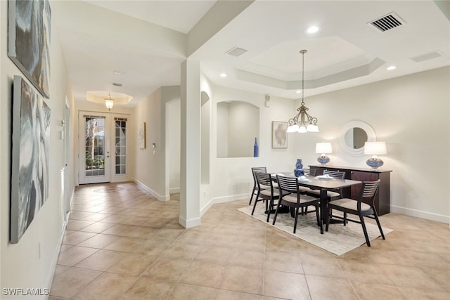 dining room featuring a notable chandelier, light tile patterned flooring, a tray ceiling, ornamental molding, and french doors