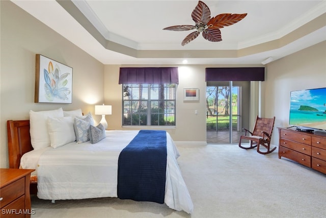 carpeted bedroom featuring ceiling fan, access to exterior, multiple windows, and a tray ceiling