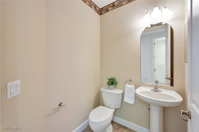 half bath featuring tile patterned floors, toilet, and baseboards