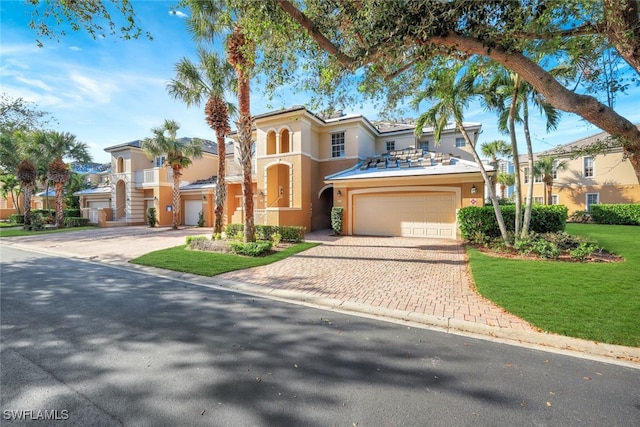 mediterranean / spanish-style house featuring stucco siding, decorative driveway, a residential view, and an attached garage