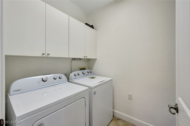 laundry room with washing machine and dryer, cabinets, and light tile patterned flooring