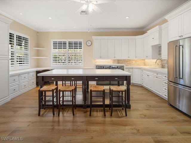 kitchen featuring white cabinets, a kitchen breakfast bar, a center island, and high quality fridge