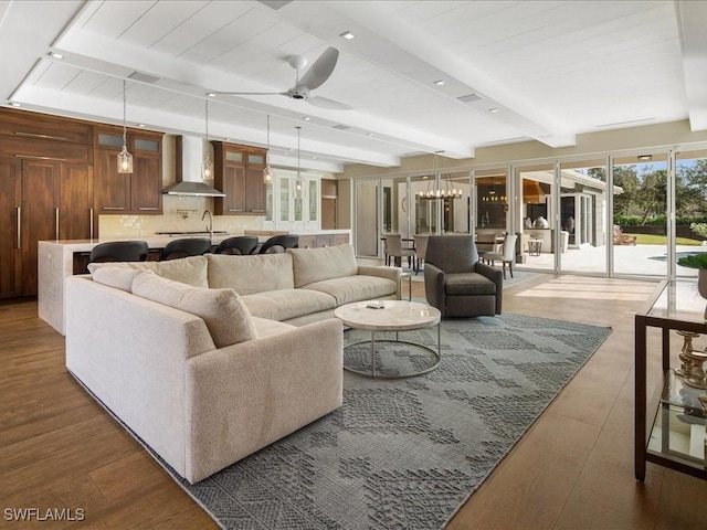 living room with beam ceiling, ceiling fan with notable chandelier, and sink