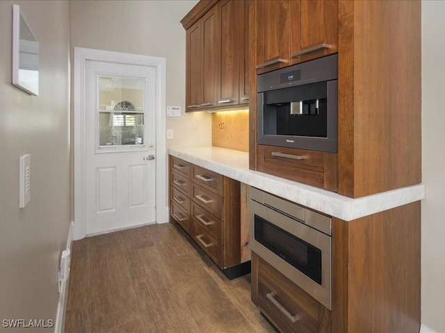 kitchen with decorative backsplash, dark hardwood / wood-style flooring, and stainless steel microwave