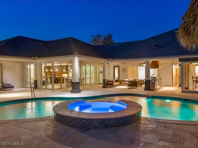 pool at twilight with an in ground hot tub, exterior kitchen, an outdoor living space, and a patio