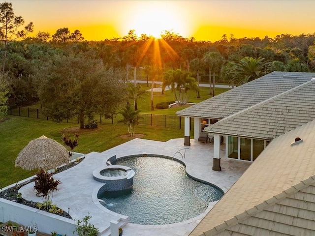 pool at dusk with a lawn, an in ground hot tub, and a patio