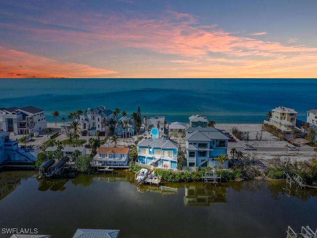 aerial view at dusk featuring a water view