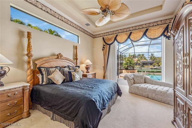 carpeted bedroom featuring a raised ceiling, ceiling fan, and ornamental molding