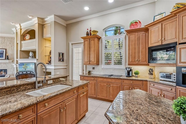 kitchen featuring sink, light stone counters, a fireplace, black appliances, and ornamental molding