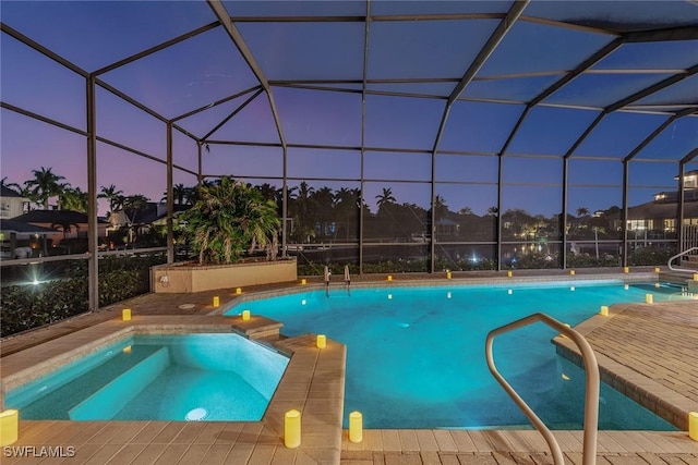 pool at dusk with an in ground hot tub, a patio, and a lanai