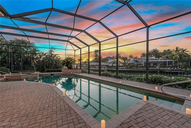 pool at dusk featuring a lanai, an in ground hot tub, and a patio