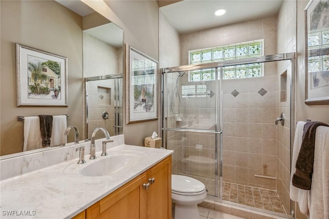 bathroom with tile patterned flooring, vanity, toilet, and walk in shower