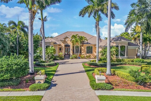 mediterranean / spanish-style house with decorative driveway, a tile roof, and stucco siding