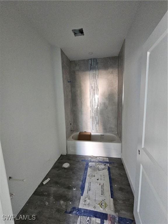 bathroom with a textured ceiling and tiled shower / bath combo