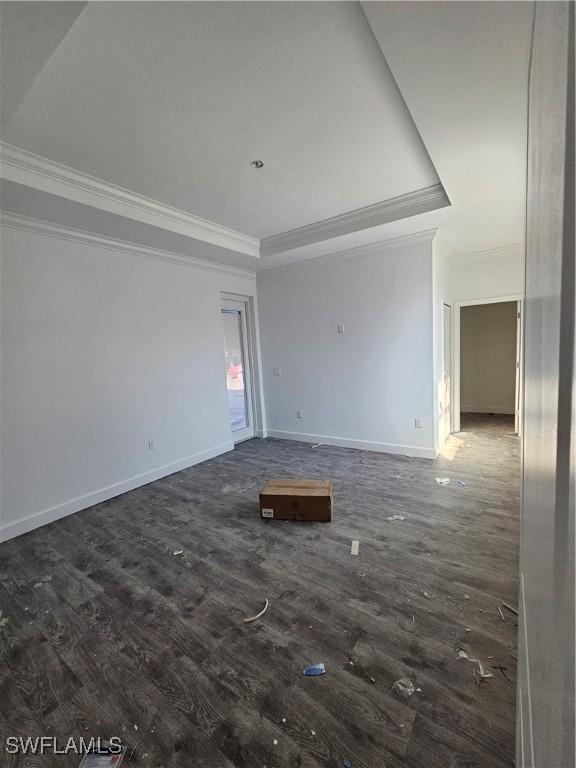 empty room featuring dark hardwood / wood-style flooring, ornamental molding, and a tray ceiling