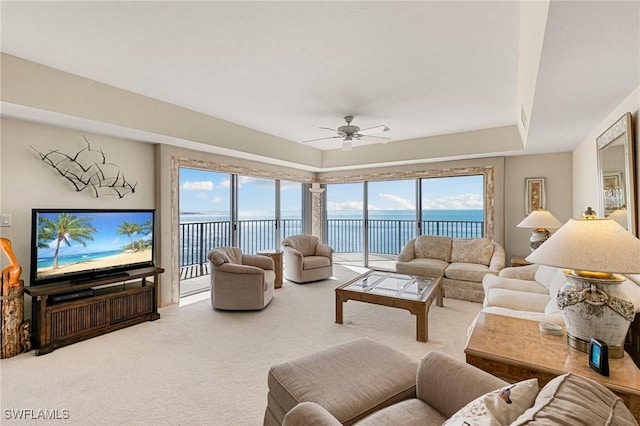 living room with ceiling fan, a water view, and carpet floors