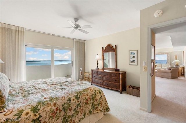 carpeted bedroom featuring access to outside, multiple windows, ceiling fan, and a water view