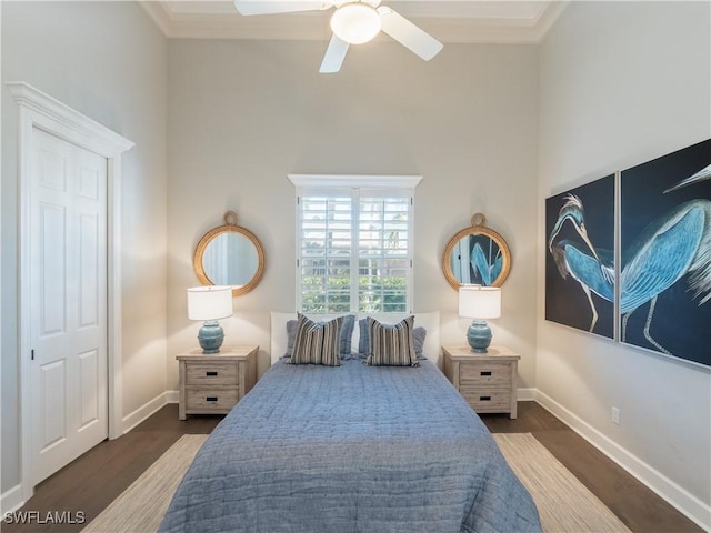 bedroom with dark wood-type flooring, a high ceiling, a closet, ornamental molding, and ceiling fan