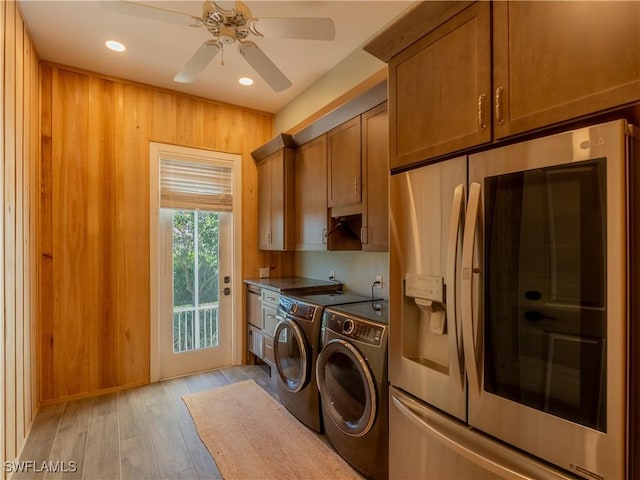 washroom featuring washing machine and dryer, wood walls, light wood-type flooring, cabinets, and ceiling fan